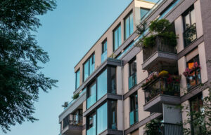 Exterior view of a modern multi-story condo building with greenery on balconies, representing the Miami new construction real estate market.