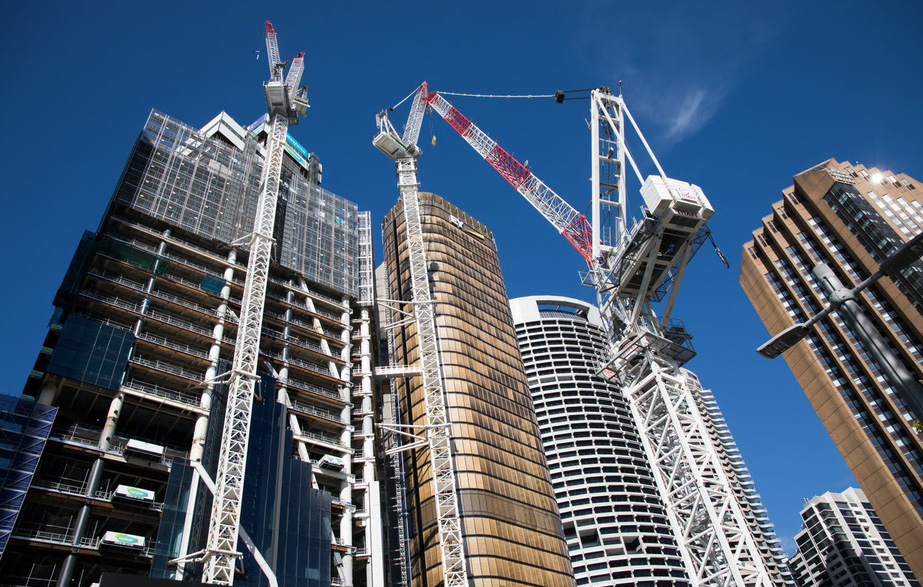 Modern high-rise condominium buildings under construction with massive tower cranes against a clear blue sky, illustrating pre-construction real estate development.